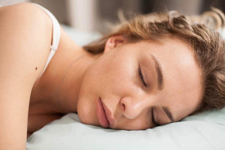 Una mujer duerme de lado en una almohada